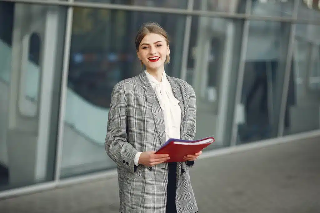 happy female with papers near office building