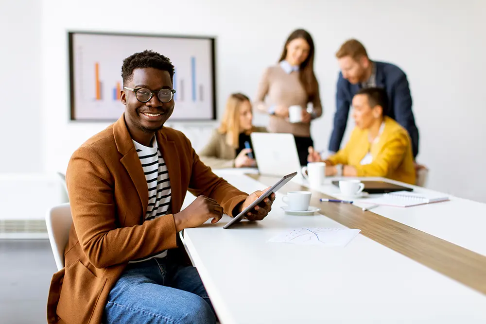 Handsome young African American business man working with digital tablet in front of his coworkers at boardroom