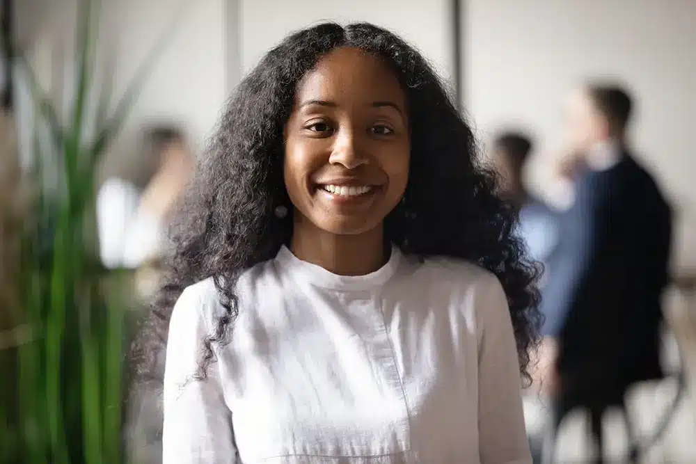 young African American business woman stands in front of the camera smiling