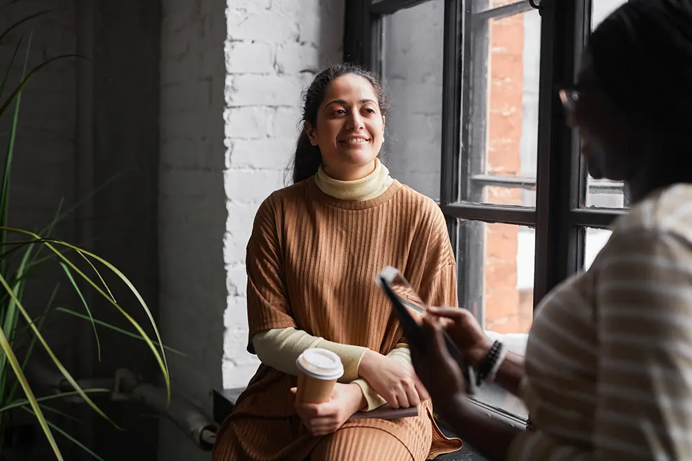 Business women sit near window in conversation