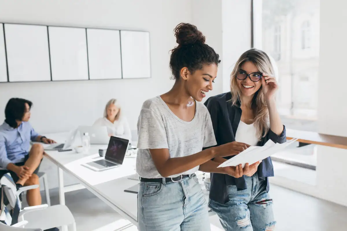 two female employees smiling and reviewing results together