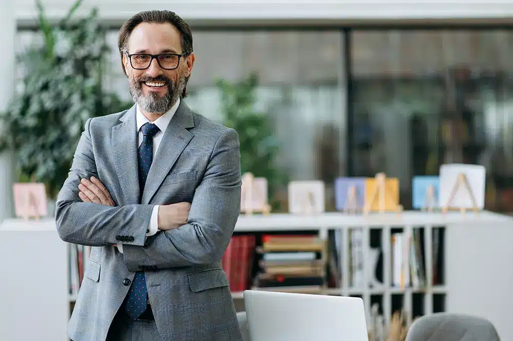 man standing with arms folded and smiling