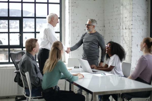 cheerful colleagues shaking hands during meeting in modern room