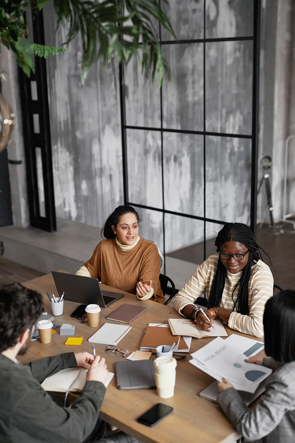 group of woman and one man meeting around a conference room table with papers