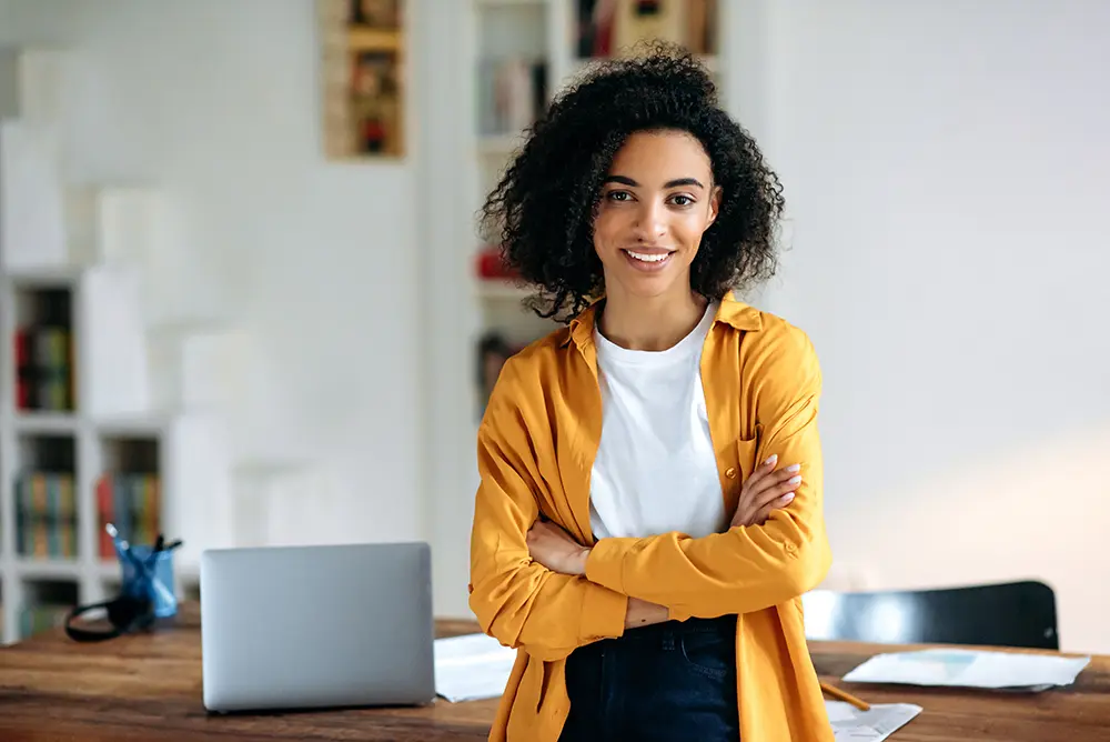 Woman standing near desk folding arms