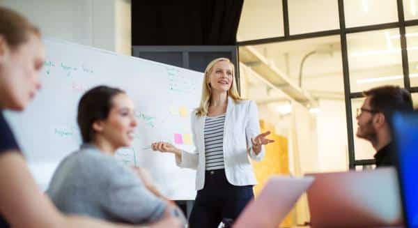 Woman presenting at whiteboard in front of group