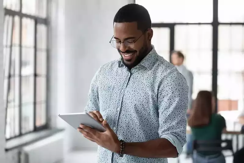 young african american man smiling and reading a tablet