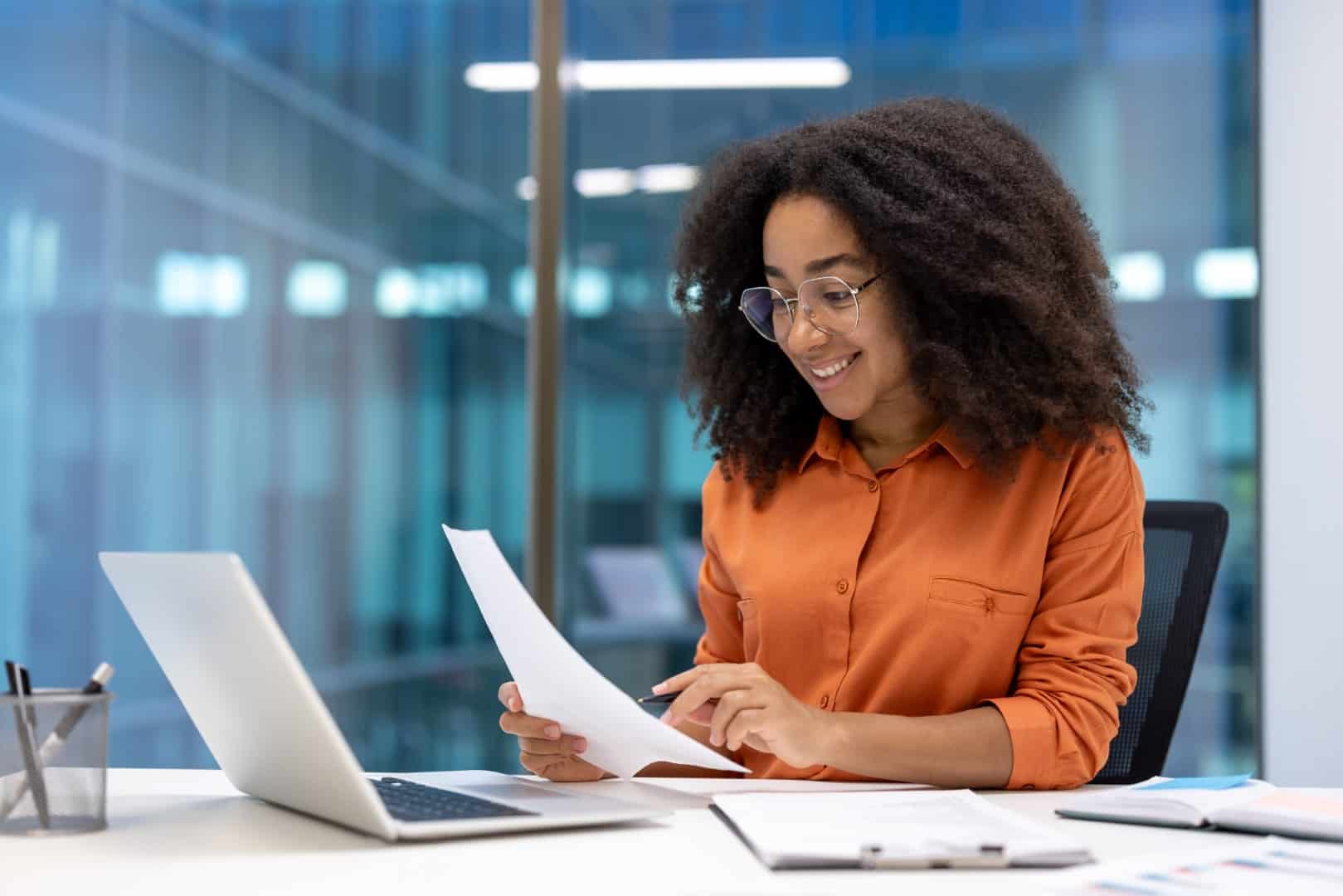 woman reviewing 360 feedback reports on laptop and paper