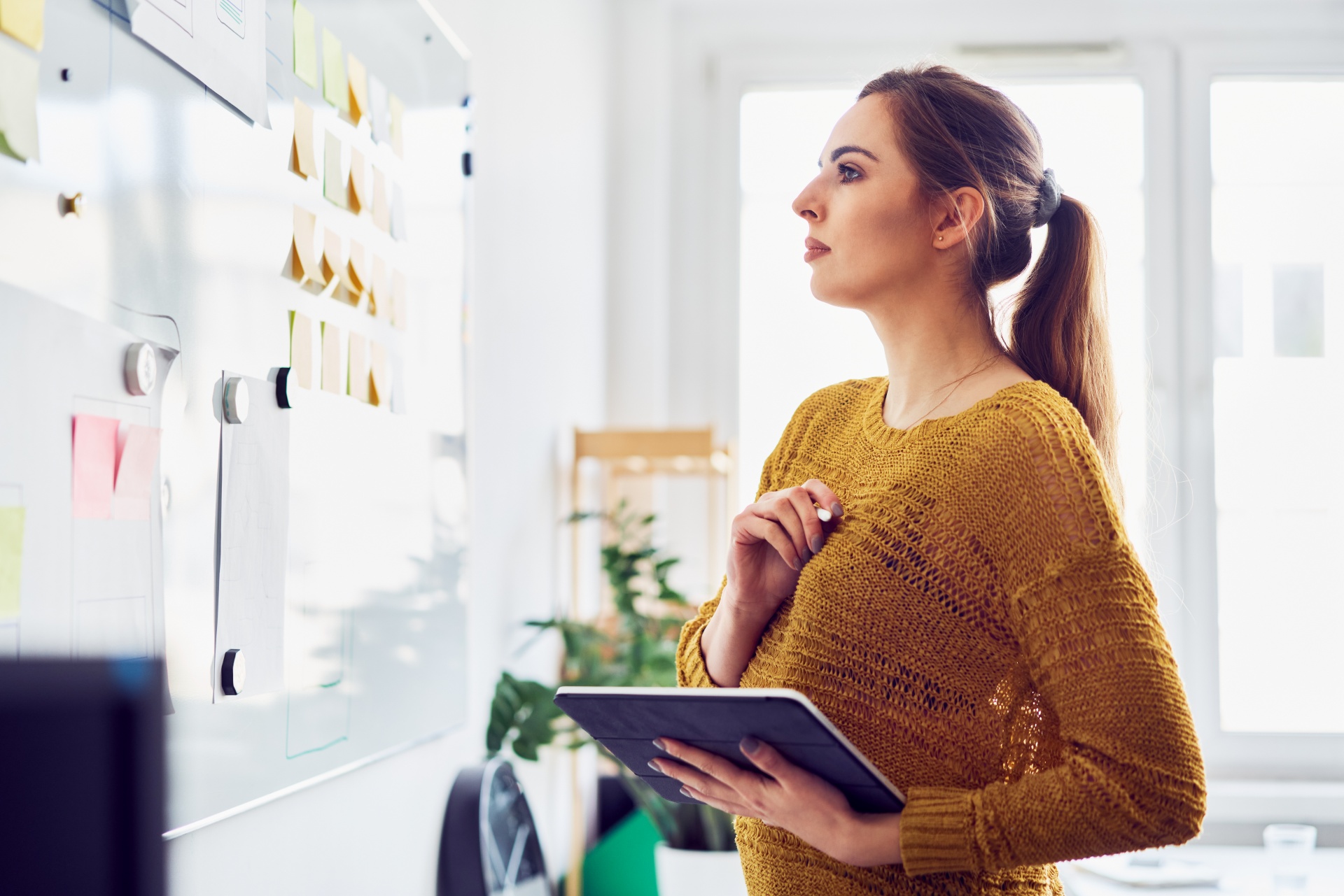Business Women Looking at Notes on Whiteboard Business woman staring at notes and writing on a whiteboard